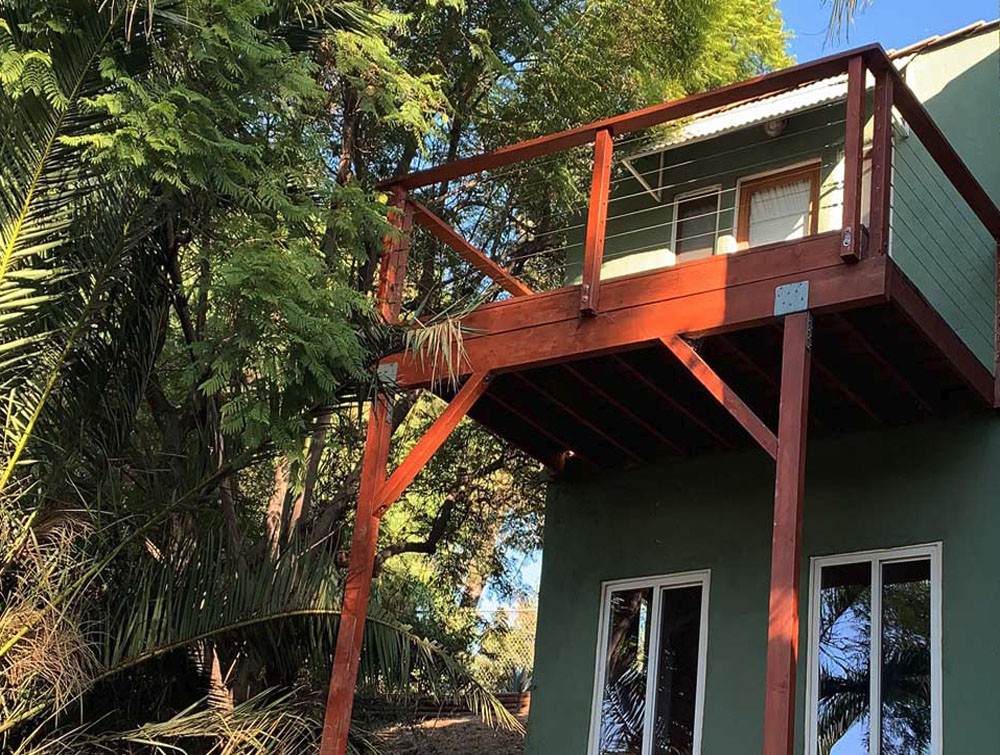 A structurally sound elevated deck finished with a modern glass railing system, providing unobstructed views, enhanced safety, and a clean, high-end appearance.