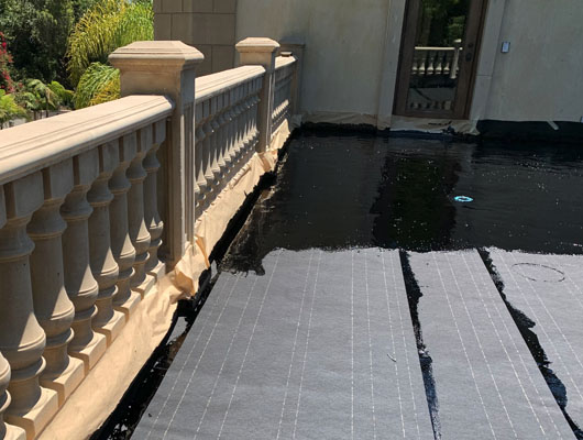 Custom waterproof deck tile installation featuring exterior stone tile work and hot mop waterproofing system